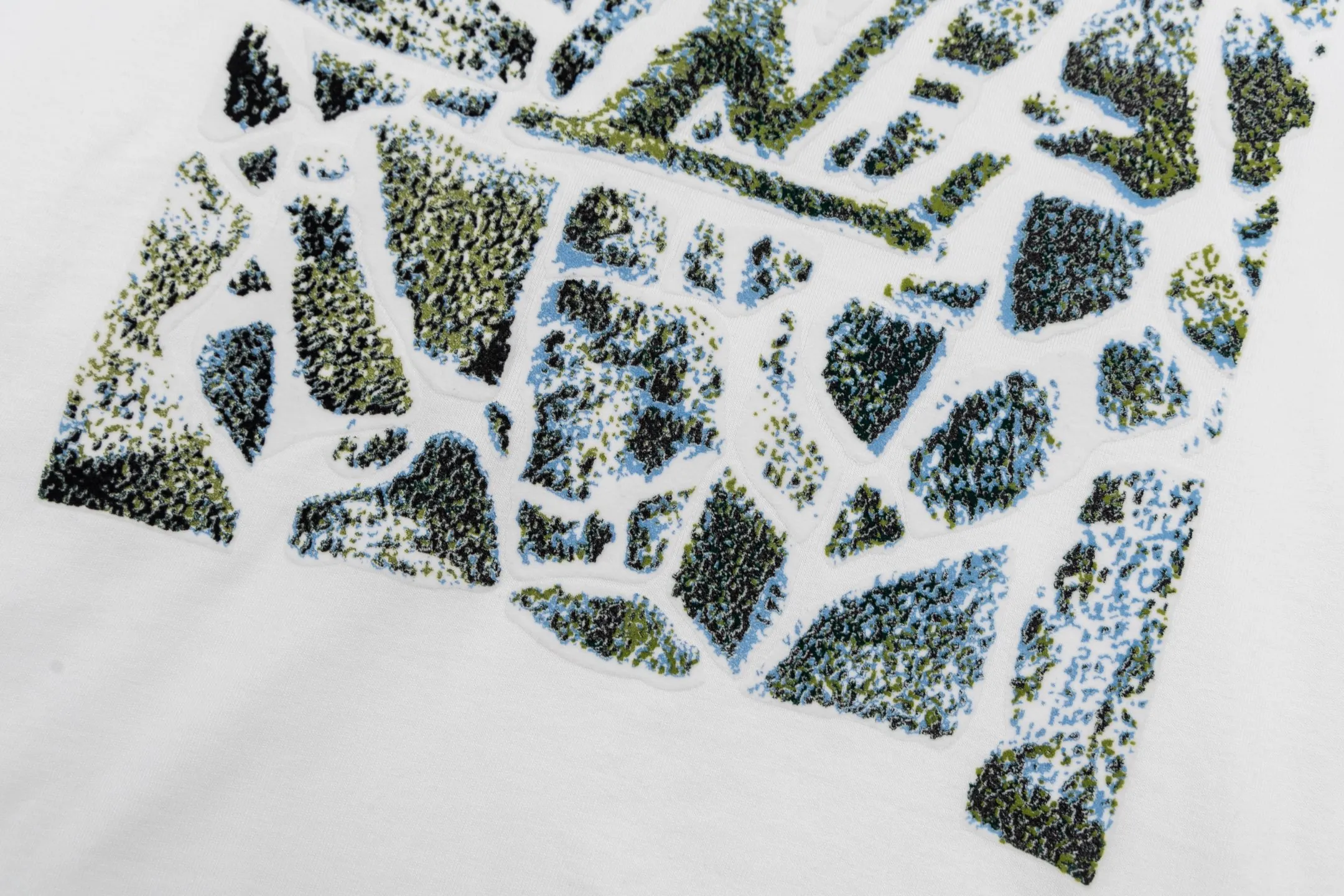 🅿️300 1v SKI ski series velvet jacquard foam short sleeves. The fabric is made of 15S 230g fine cotton plain fabric, and the rib is made of 32S 380g double yarn rib. This T-shirt is made of elegant cotton with a richly textured velvet 1V pattern on the front, depicting rock peaks, snowfields and forest scenes. The crack effect simulates a forest path, and the 1V logo is implicitly embellished in the center. The avant-garde and elegant shape embodies the casual style of winter. The base is made of 15-count combed cotton jersey fabric, with a weight of 230g/㎡, giving it a flexible texture and excellent morphological stability. Short lint impurities are removed through the combing process to ensure the smoothness of the cloth surface and yarn strength. Combined with high-density weaving, the fabric has a delicate and smooth texture, providing an ideal canvas for subsequent complex printing. The surface of the fabric is smooth and delicate, and the texture is tight. The fabric has good softness and comfort, stable breathability, and can keep the body dry. The pattern is realized through overprinting of more than six colors of velvet slurry. In the gradient transition between rock peaks, snowfields and forests, by adjusting the density of velvet powder and the thickness of the slurry, a micro-three-dimensional suede surface drop of 0.2-0.5mm is formed. The snow peak area uses high-reflective velvet pulp to create a cold texture, and the forest part uses dark thick slurry accumulation to simulate vegetation levels. The crack effect uses the slurry blanking technique to tear out a visual channel to the base fabric in the suede matrix. Size:XS-S-M-L